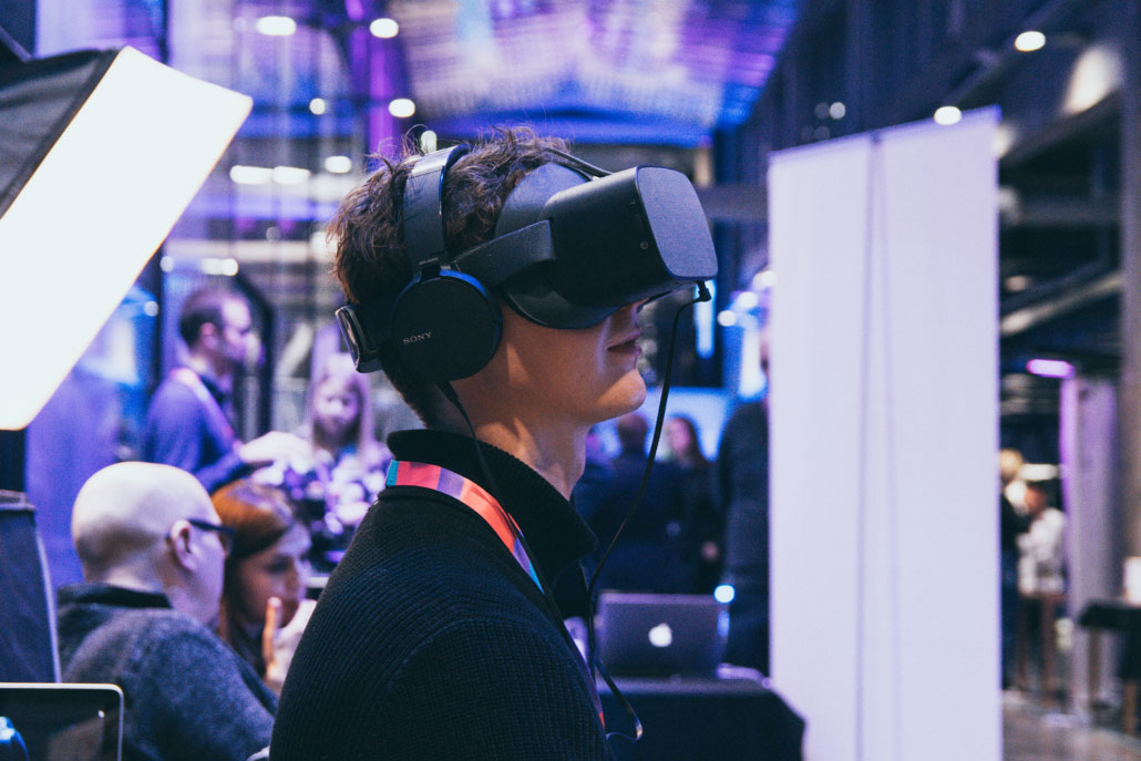 A man with a virtual reality headset on his head is looking up.