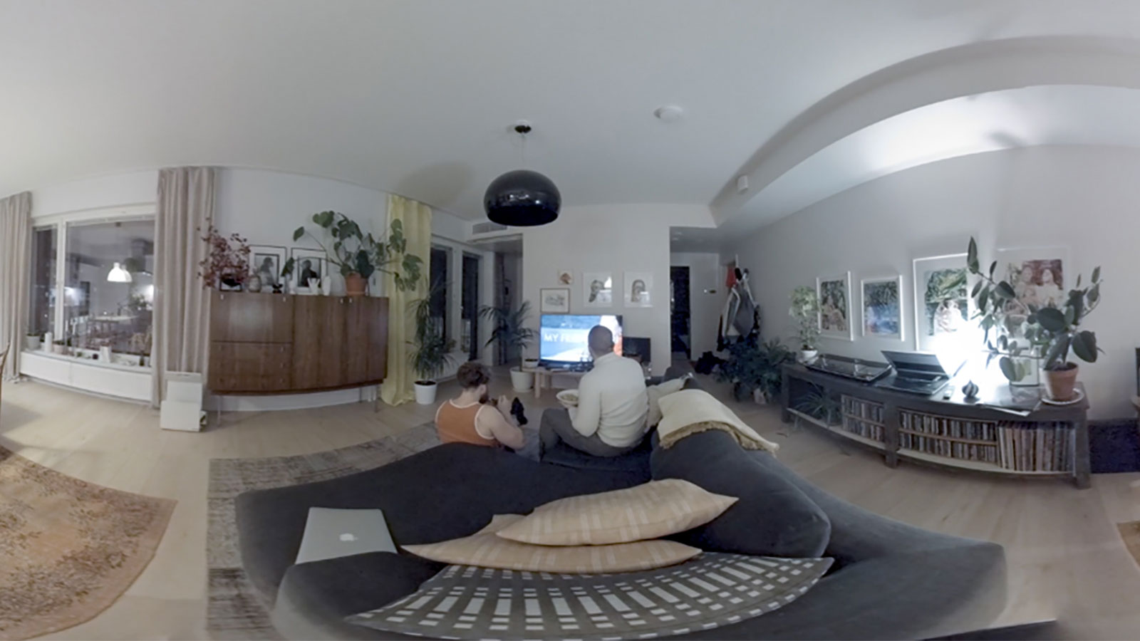 A screenshot from a 360 degree documentary project made by XR Hub team 361. Somebody's living room with two people sitting on the couch and watching tv.