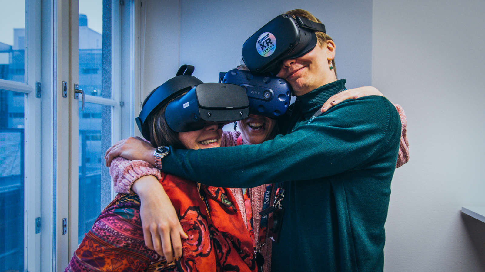Three people hugging while wearing VR headsets.