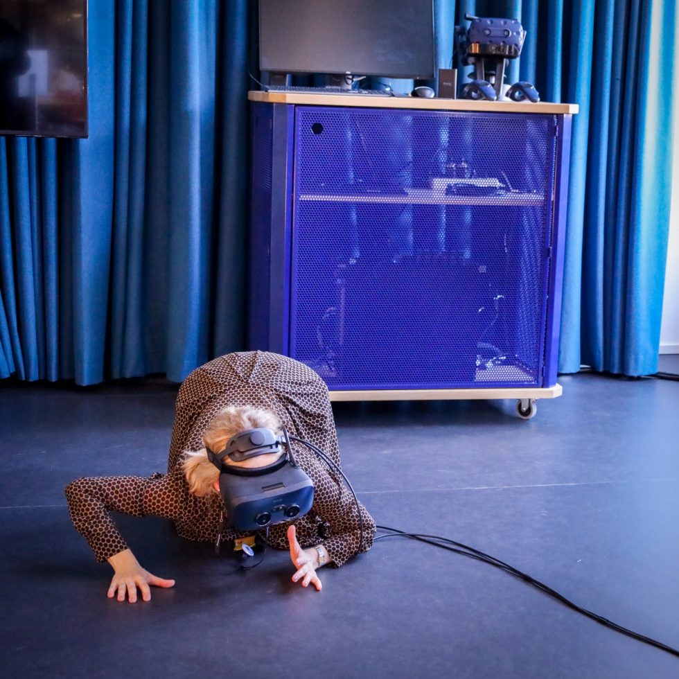 A person wearing a VR headset is crawling on the floor.