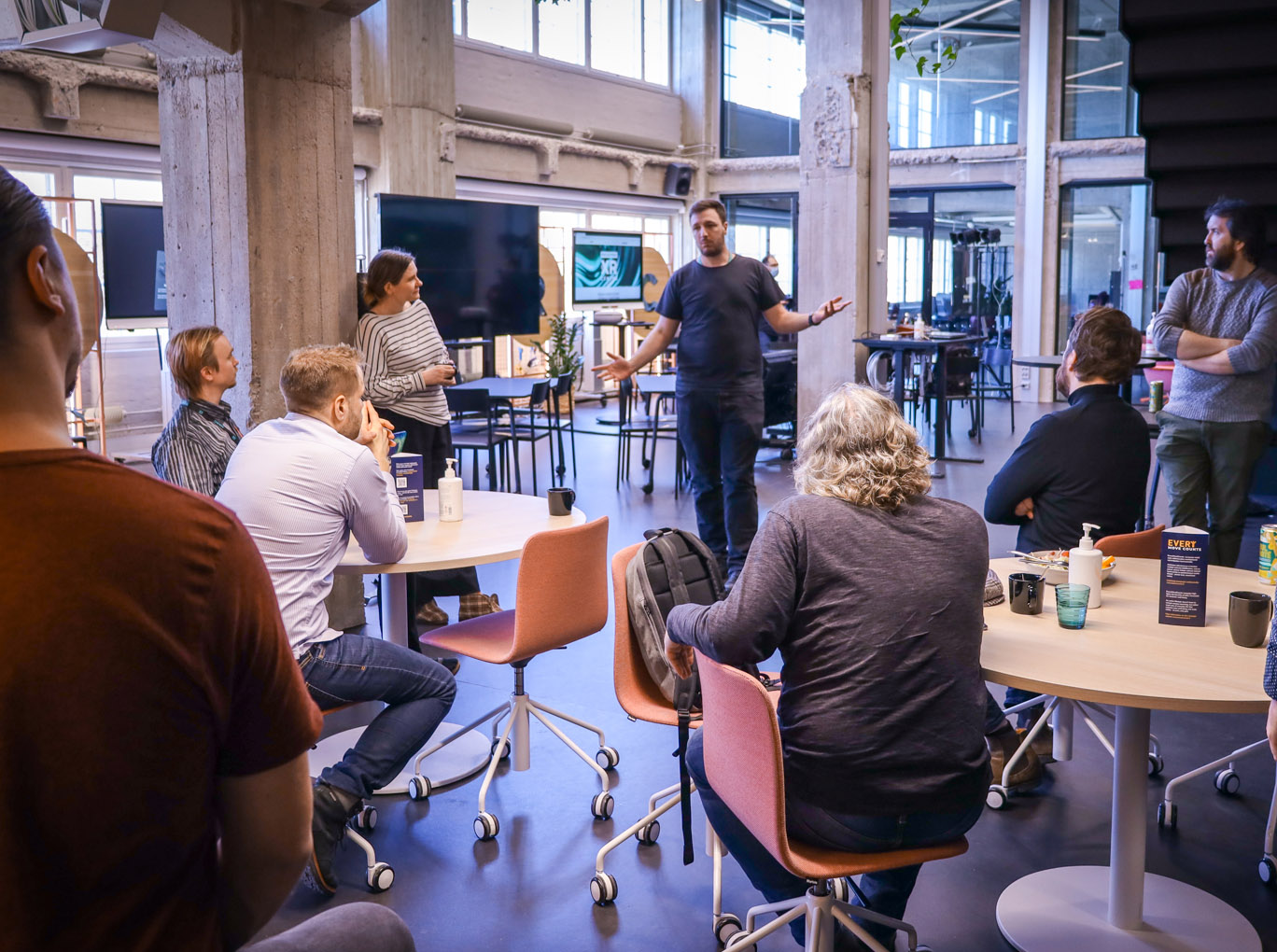 Networking at Helsinki XR Center premises. One person is talking standing up, and others are sitting and listening.